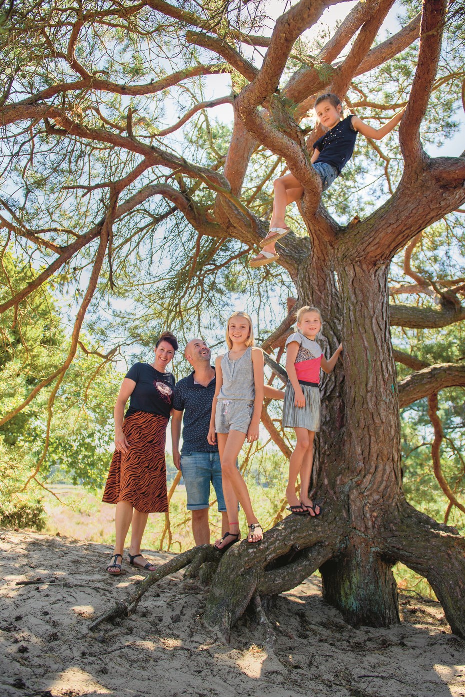 Man en vrouw met hun drie dochters rondom boom