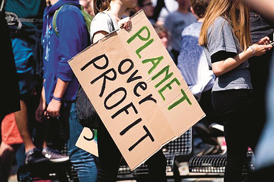 Vrouw met bord in de hand met de tekst 'Planet over profit'